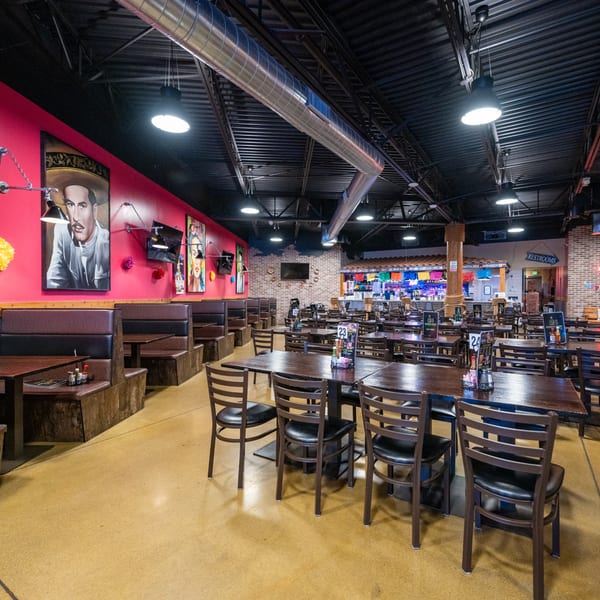 Spacious Mexican restaurant interior with red walls, booths, tables, chairs, and vibrant decor.
